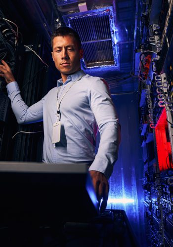 Serious concentrated qualified male IT technician configuring operating system on physical servers